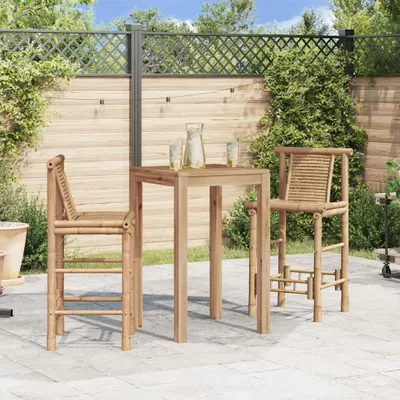 A patio scene with a bar table and two bar stools made of bamboo, set against a wooden fence and greenery.