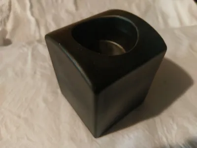 Ein mittelgroßer, quadratischen Teelichthalter aus schwarzer Keramik.