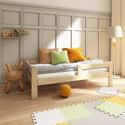 A child's bedroom with a wooden bed, pillows, and a floor lamp.