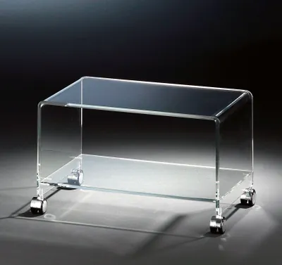 A clear acrylic TV stand with chrome wheels on a dark background.