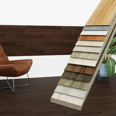 A display of vinyl flooring samples in various wood-like finishes, with a chair and plant in the background.
