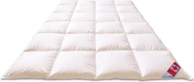 A white down comforter is laid out on a white background, showing its quilted pattern. A small Canadian flag tag is visible on the bottom right corner.