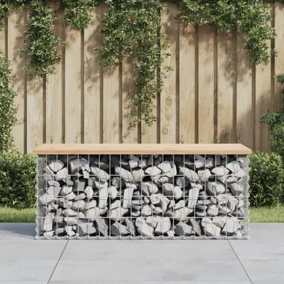 A gabion bench with a wooden top sits on a patio in front of a wooden fence with ivy growing on it.