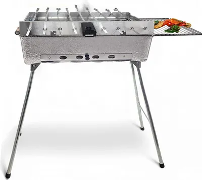 A stainless steel barbecue grill with folding legs, skewers, and a small rack of vegetables on the side.