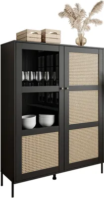 A black display cabinet with cane detailing and glass doors, standing on thin black legs. It is decorated with two wooden crates and a vase of dried flowers on top.
