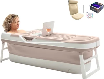 A woman is relaxing in a portable bathtub with a laptop and a glass of wine.