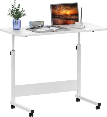 A white adjustable height rolling laptop table with a laptop, book, and coffee cup on it.