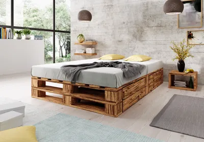 A bedroom scene featuring a pallet bed with storage drawers, bedside table, and decor.