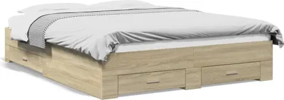 A wooden bed frame with drawers, covered with white bedding and a gray and white patterned throw.