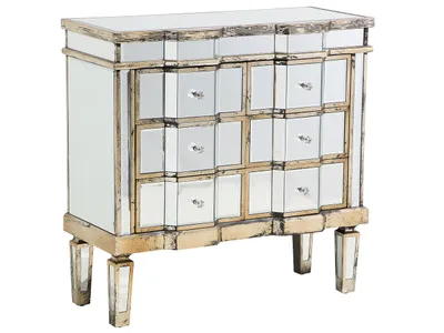 A mirrored chest of drawers with gold accents and crystal knobs, presented on a white background.