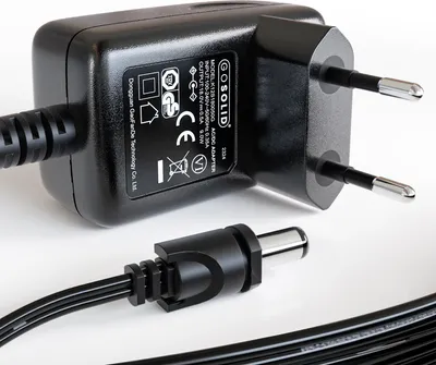 A close-up studio shot of a black AC/DC adapter and its attached connector.
