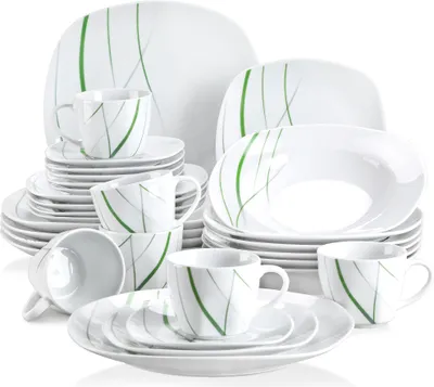 A collection of white ceramic dinnerware with green line accents, arranged in a studio shot.