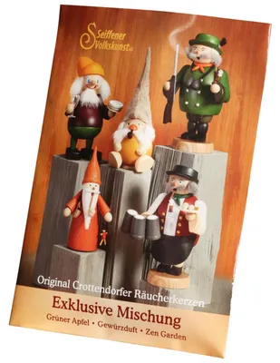 Auf dem Bild ist eine Verpackung von Original Crottendorfer Räucherkerzen mit der Aufschrift Exklusive Mischung zu sehen die verschiedene Figuren und die Duftnoten Grüner Apfel Gewürzdüft und Zen Garden zeigt