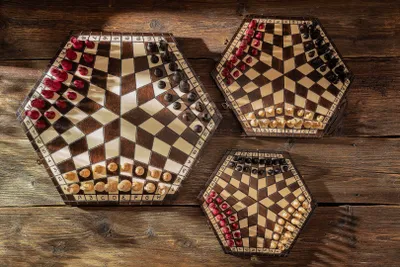 Three hexagonal chessboards of different sizes are arranged on a wooden surface.