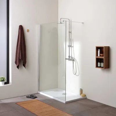 A modern bathroom with a walk-in shower, towel, and shelving unit.