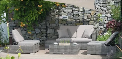 An outdoor seating area with a stone wall and lush greenery.
