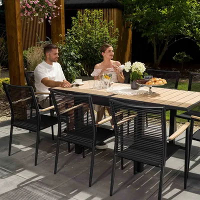 A couple is sitting at a dining table in a garden setting.