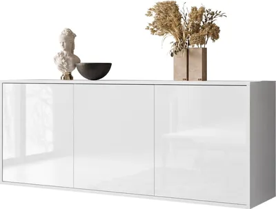 A white, high-gloss sideboard with three doors, decorated with a bust, a bowl, and a vase with dried flowers.