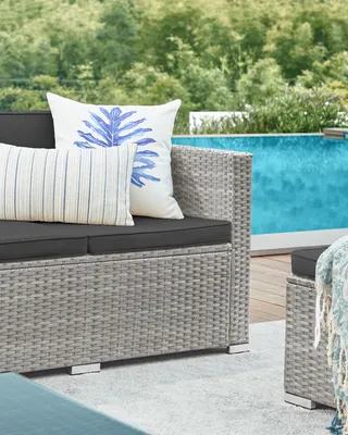 A close-up view of an outdoor lounge set with cushions and pillows next to a swimming pool.