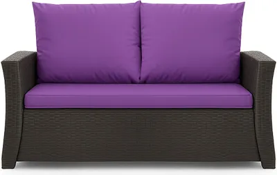 A studio shot of a brown rattan sofa with purple cushions.