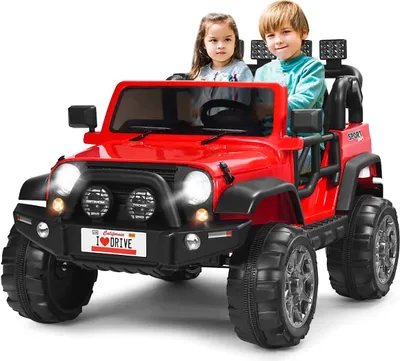 Two children are sitting in a red toy electric car.