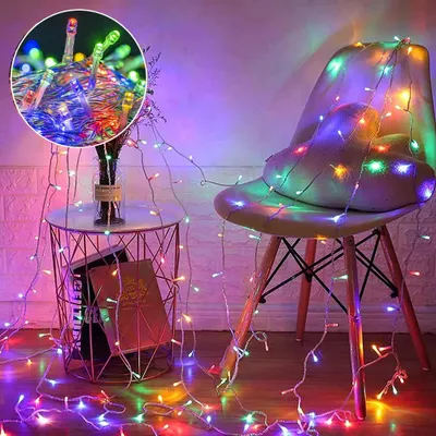 A string of colorful LED lights draped over a chair and a side table, with a vase of flowers on the table.
