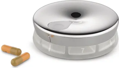 A pillbox with two pills next to it.
