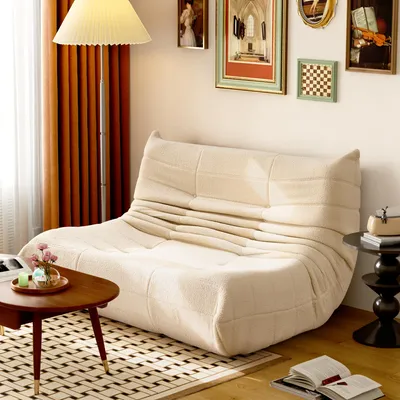 A cozy living room scene featuring a beige sofa, a coffee table with decorative items, and artwork on the wall.
