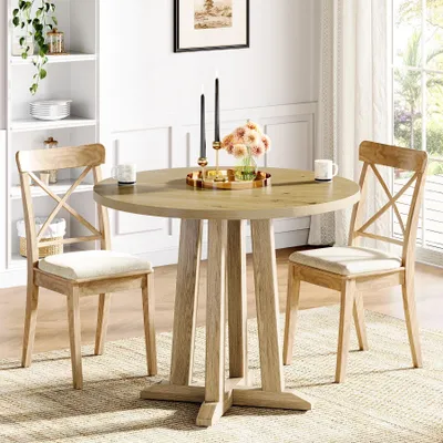 A round wooden dining table with two chairs in a well-lit room, with a bookshelf in the background.