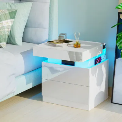 A white bedside table with LED lighting next to a bed.
