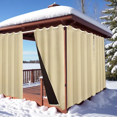 A gazebo covered in snow with beige curtains hanging.