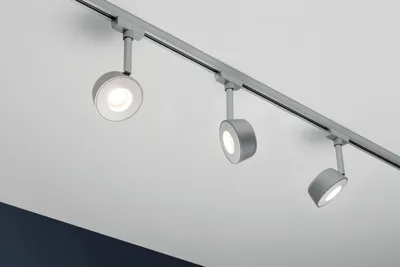 Three track lights mounted on a rail system against a white ceiling.