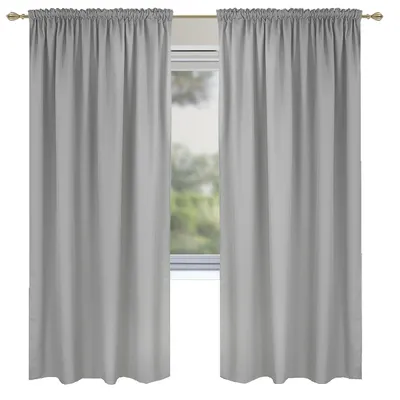 Two light gray curtains hanging on a curtain rod in front of a window with greenery visible outside.