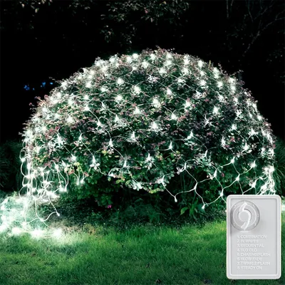 A bush decorated with white net lights at night.