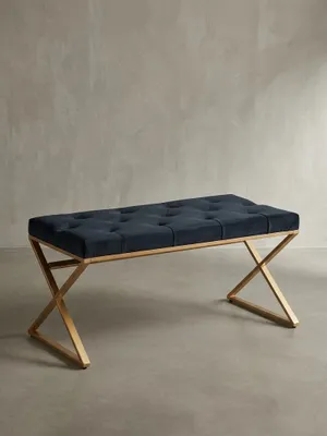 Frontalansicht der Design-Sitzbank mit schwarzem Samtpolster und gekreuztem Gestell aus goldfarbenem Edelstahl, freigestellt auf weißem Hintergrund._#sku_BARWL6.617#