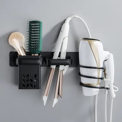 A wall-mounted organizer for hair styling tools, including a hairdryer, straighteners, a brush, and a makeup brush.