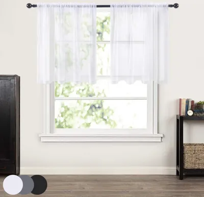 A window with white sheer curtains hanging on a rod, with a dark cabinet to the left and a small shelf with books and a clock to the right.