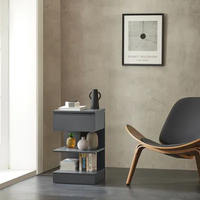 A modern living room scene featuring a gray nightstand with decorative items and books, next to a stylish chair.