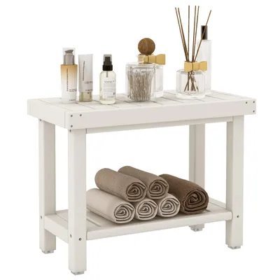 A white wooden shower bench with bathroom accessories on top and rolled towels on the shelf below.