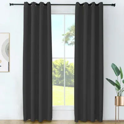 Two dark gray curtains are hanging in front of a window with trees visible outside.