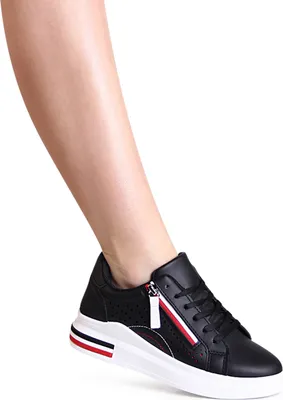 A person's leg wearing a black sneaker.