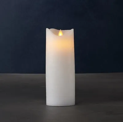 A white LED candle with a flickering flame sits on a dark surface against a dark blue background.