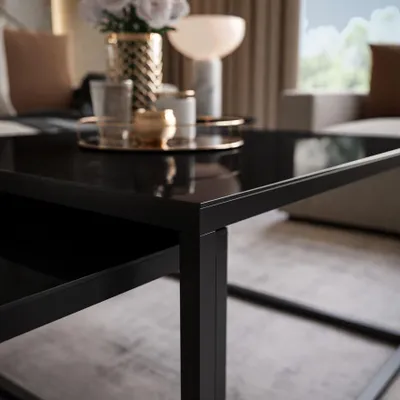 A close-up shot of a black coffee table with items on it in a living room setting.