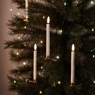 Close-up of white LED candle lights on a Christmas tree with fairy lights.