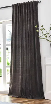 A dark brown curtain hangs in front of a window, with a white cabinet and a plant visible to the right.