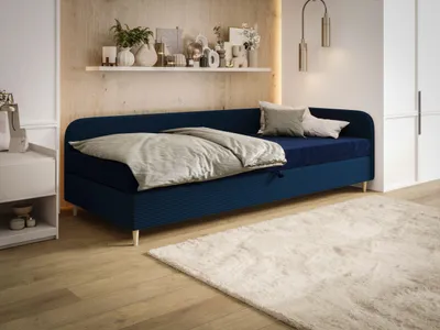 A bedroom scene with a blue daybed, bedding, pillows, a nightstand, and a rug.