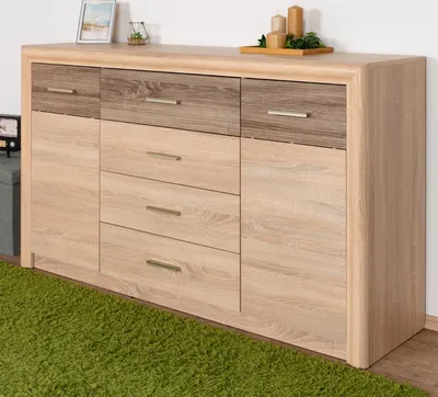 A wooden dresser with multiple drawers and doors, placed on a green carpet.