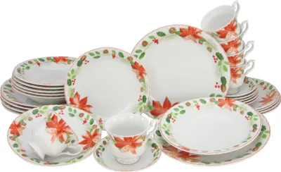 A collection of white porcelain dinnerware with a red poinsettia and green leaf pattern, including plates, bowls, and cups.