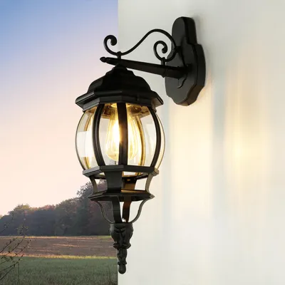 An outdoor wall lamp is mounted on a white wall, with a landscape scene in the background.