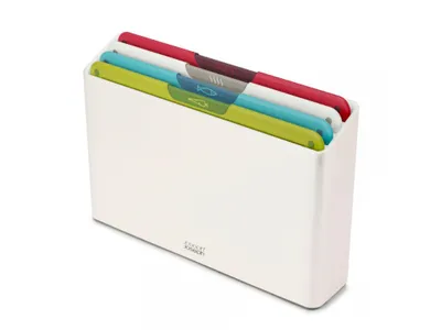 A set of four cutting boards in a white storage container.